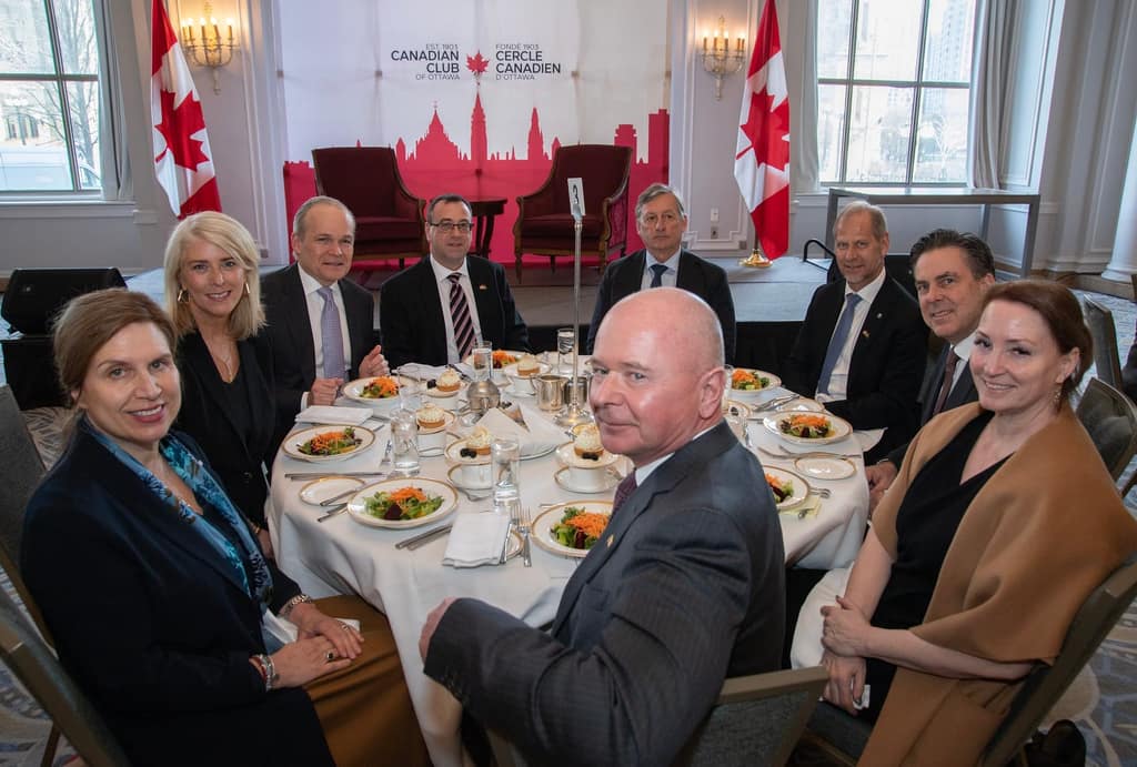 Head-table guests seated together in front of the Club’s red skyline backdrop and Canadian flags